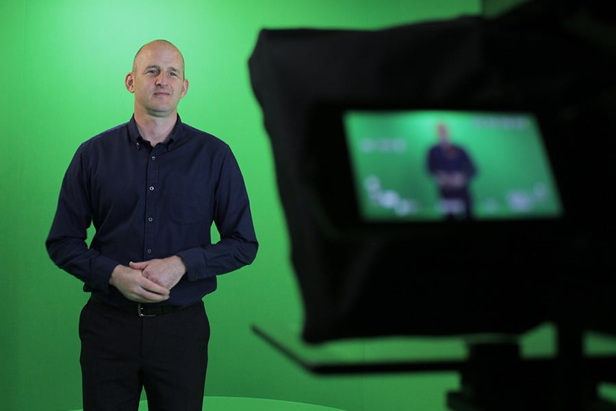 Mpirical trainier presenting an on-demand video infront of greenscreen