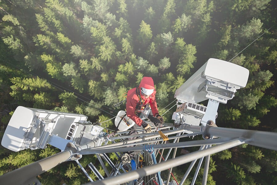 Engineer working on antenna with the forest below