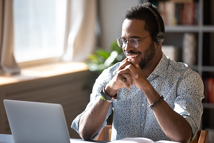Man smiling watching Mpirical on-demand video training on his laptop