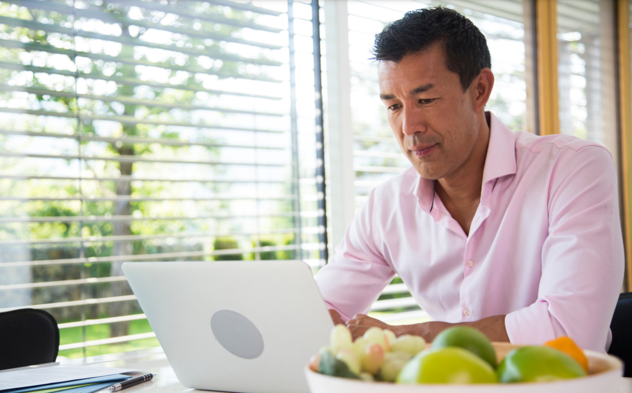 Middle aged man with laptop in kitchen
