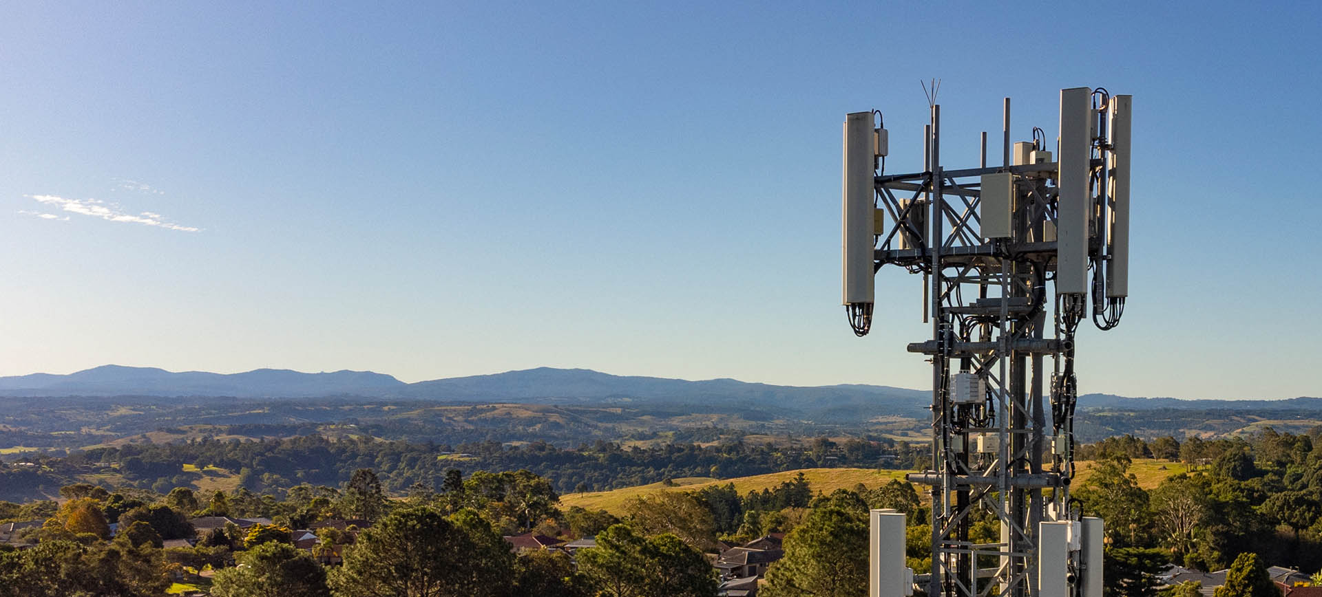 Telecoms antenna at height, hills and houses behind