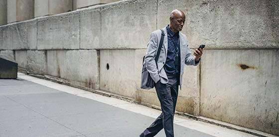 man walking down street looking at mobile phone