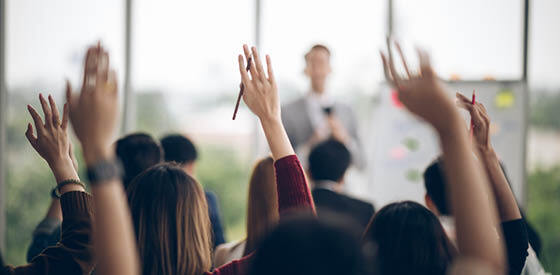 adults in a classroom setting raising their hands