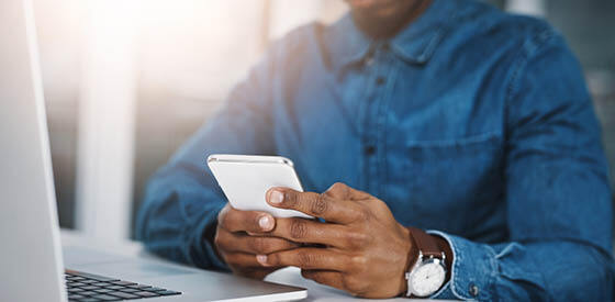 man with blue shirt and watch using cell phone