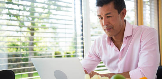 man in pink shirt looking at laptop