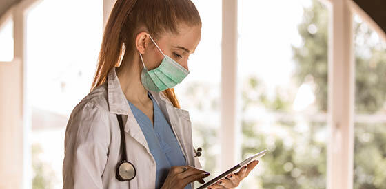 female doctor with mask using tablet device