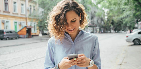 woman in blue shirt looking at mobile phone
