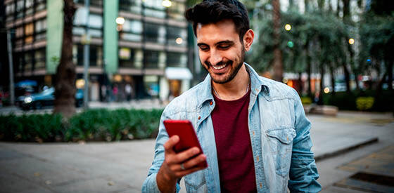 man in red shirt looking at his mobile phone